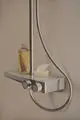 Duschsystem von Ideal Standard mit runder Handbrause, zwei Regelknöpfen und einer Ablage für Pflegeprodukte an der Wand angebracht.